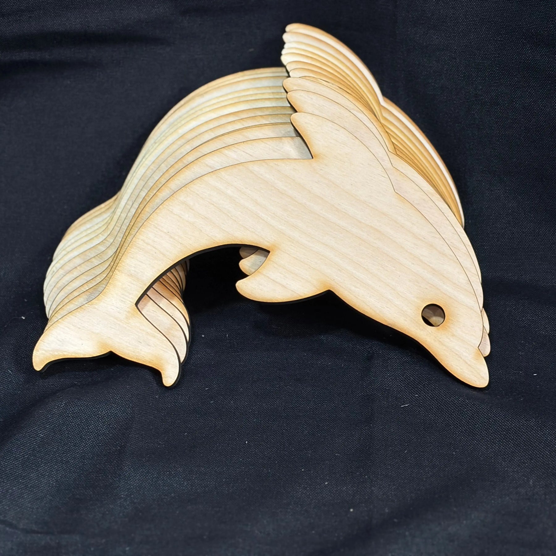 Wooden dolphin cutouts: Stack of unfinished Baltic birch plywood crafts for DIY projects.