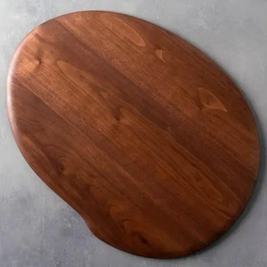 Walnut wooden lap desk with a smooth, oval shape sitting on a gray surface.