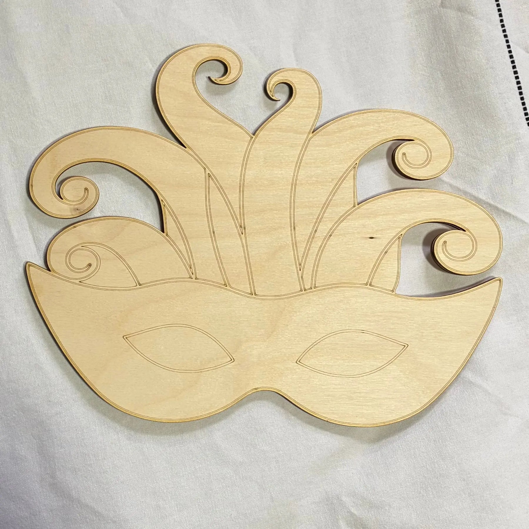 Wooden Mardi Gras mask craft blank made of Baltic birch plywood with decorative engraved lines.