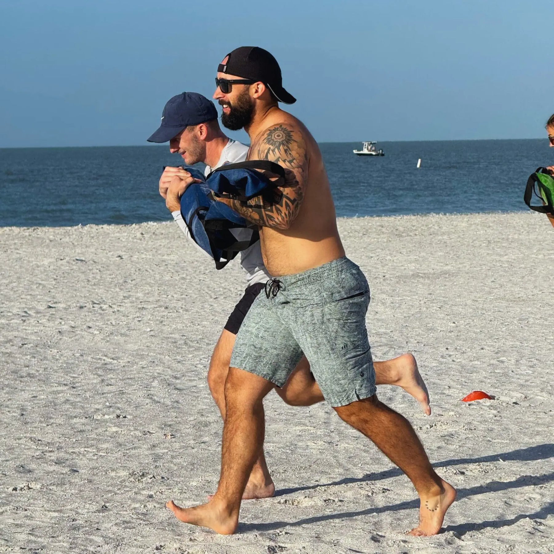 Two men performing a workout on a sandy beach with a workout battle bag.