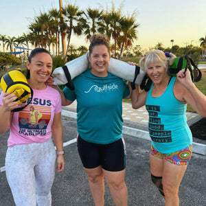 Three women holding a workout battle bag made of recycled fire hose material