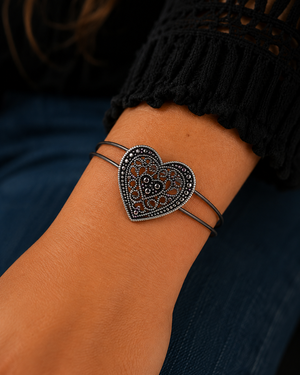 Heart-shaped bracelet on a wrist with a dark background
