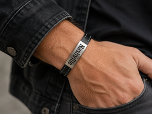 Person wearing a black and silver bracelet on a blurred background