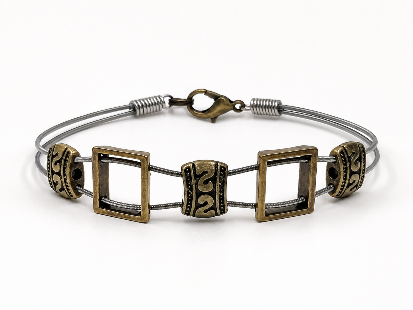 Brass bracelet with square and circular designs on a white background