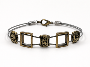 Brass bracelet with square and circular designs on a white background