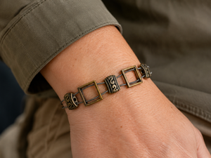 Bracelet with square links worn on a wrist, with a blurred background