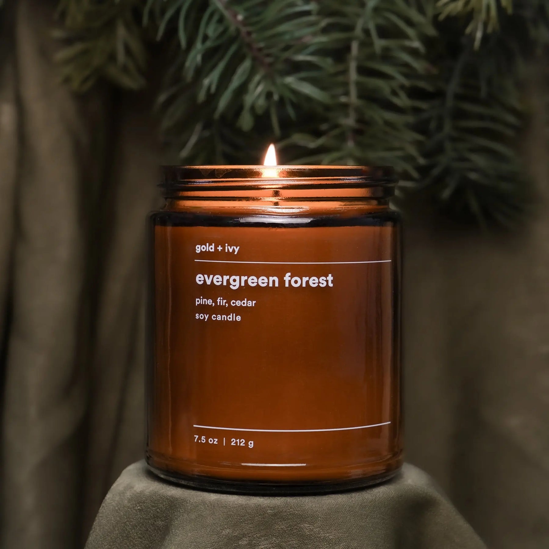 Amber glass candle labeled "evergreen forest" with pine, fir, cedar scents.
