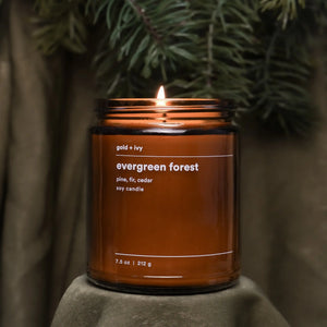 Amber glass candle labeled "evergreen forest" with pine, fir, cedar scents.