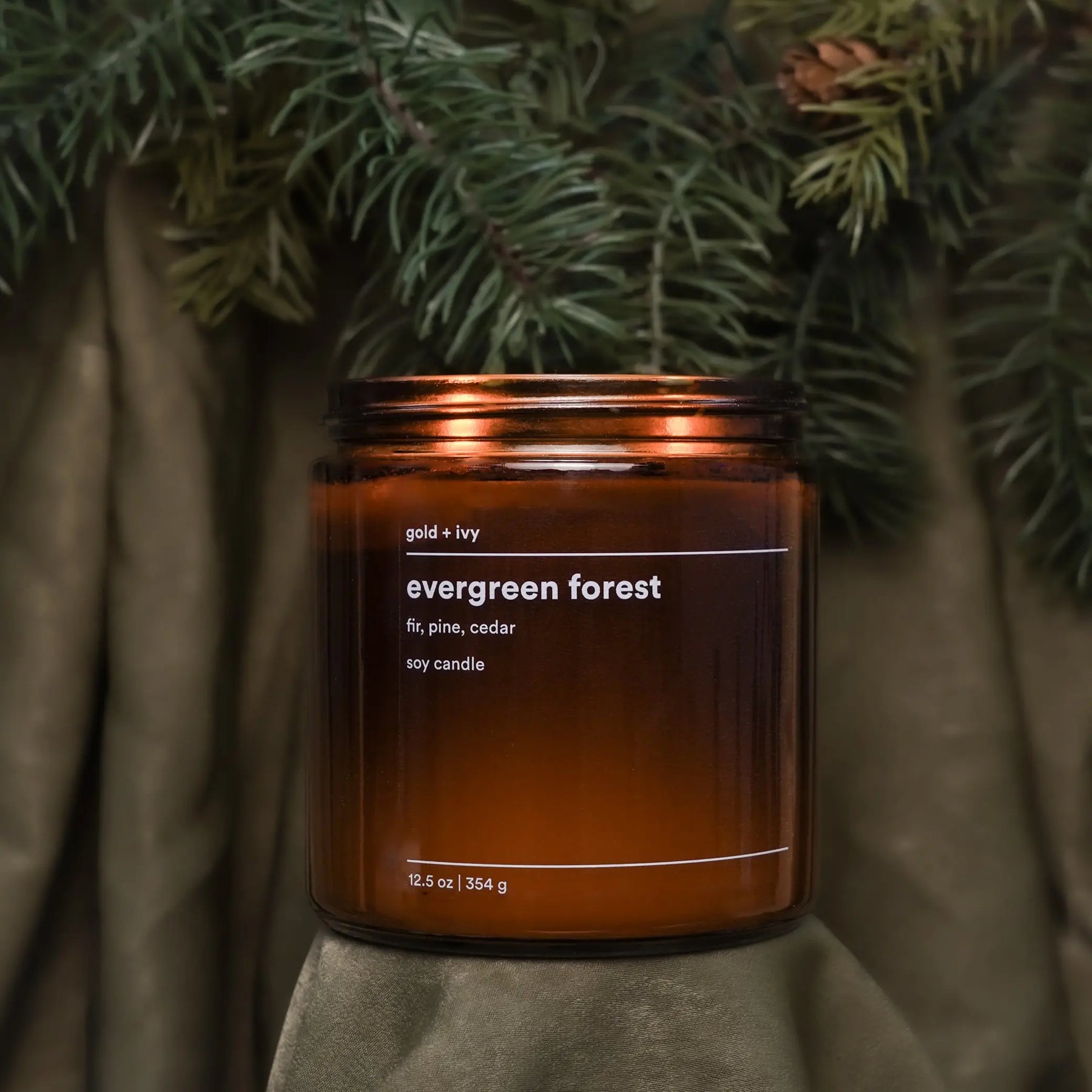 Evergreen Forest candle with fir, pine, and cedar scent in an amber glass jar.