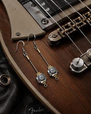 Silver and gold earrings on a Fender guitar