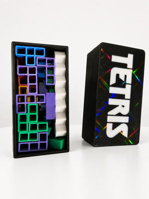 Mini Tetris style travel puzzle game box and colorful pieces on a white table