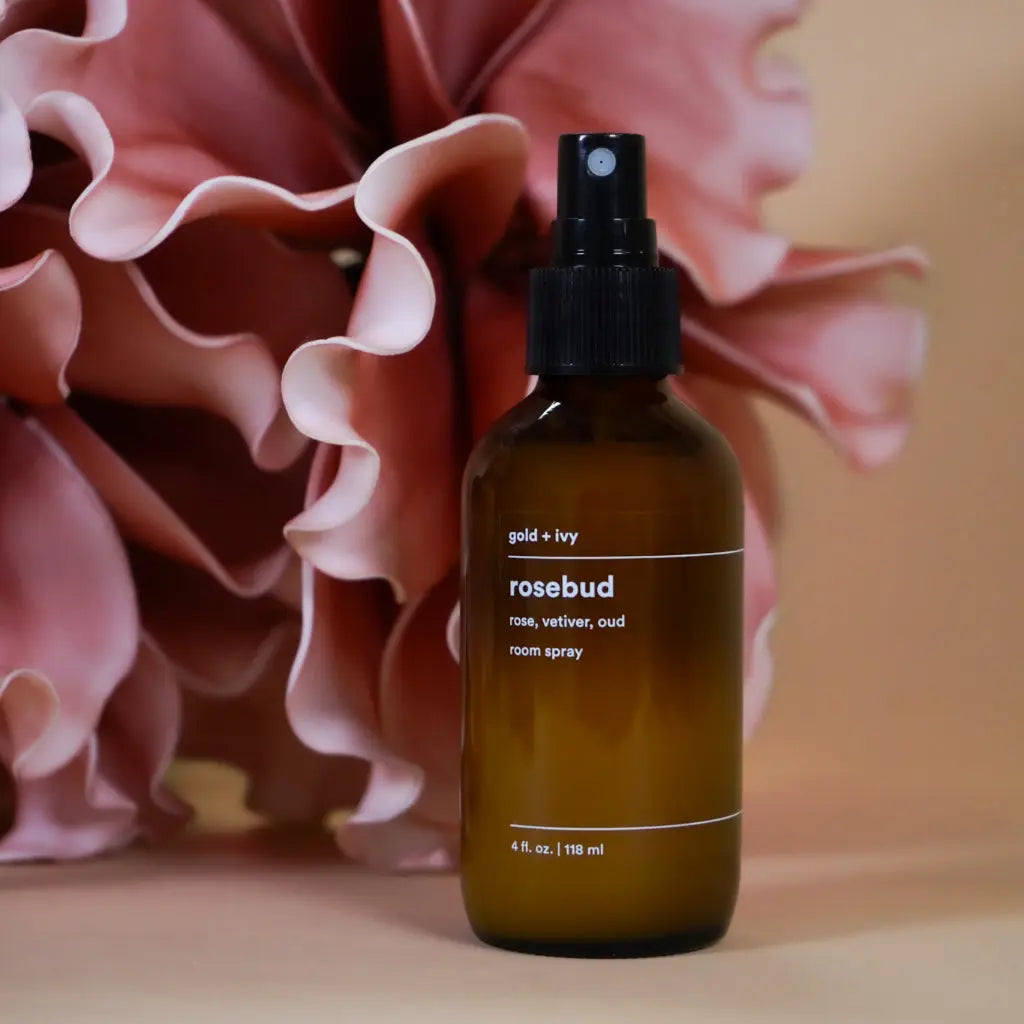 Rosebud room spray by gold + ivy in a brown glass bottle with pink flowers.