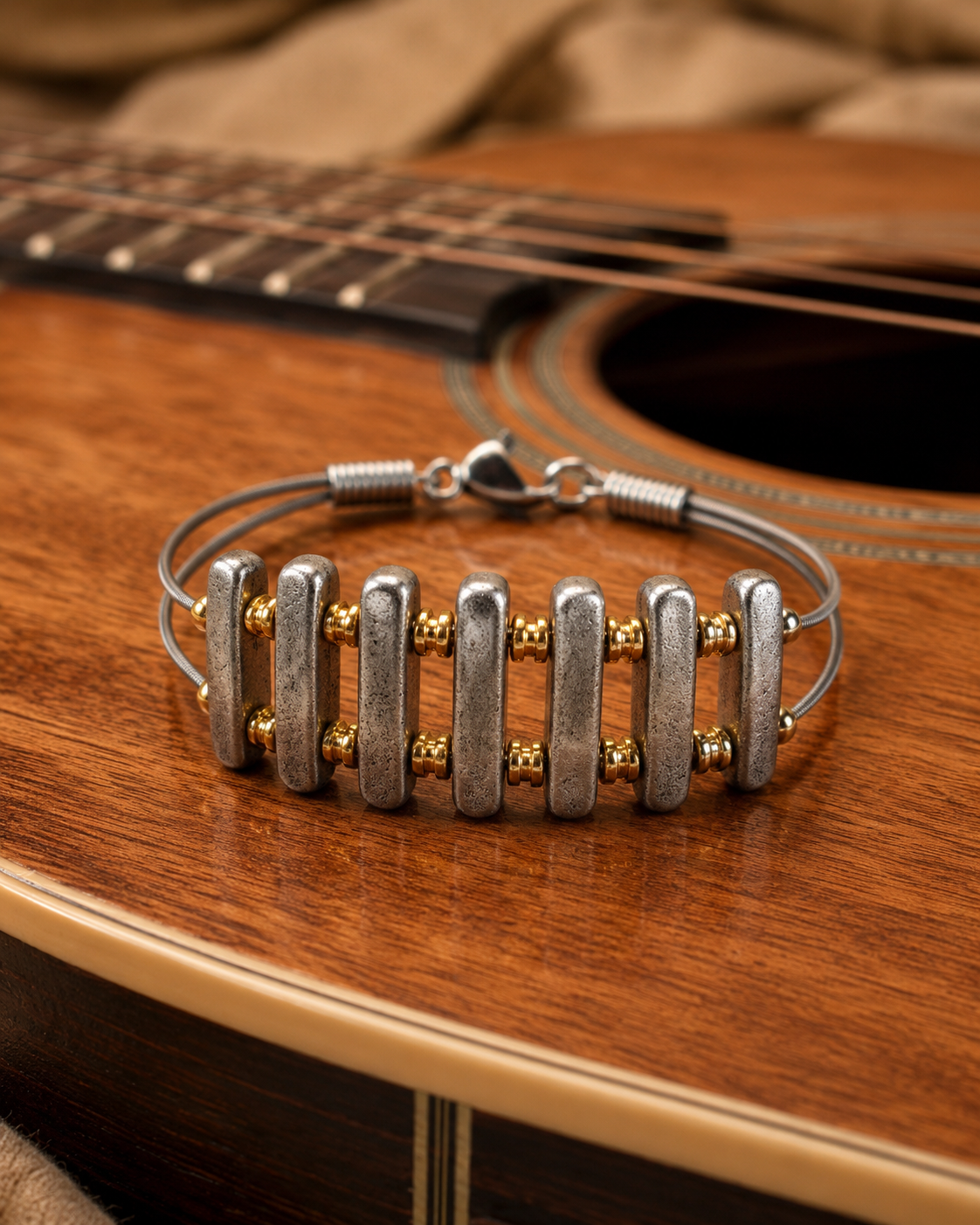 Silver and gold bracelet on an acoustic guitar