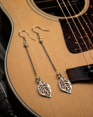 Silver leaf earrings on a guitar
